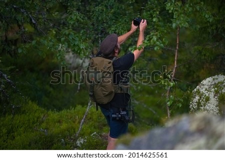A closeup shot of Caucasian man taking a picture of trees in nature in Norway