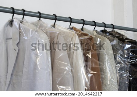Rack with clean coats after dry cleaning on a dry cleaner. Quality laundry service. Hangers row. Winter season. Royalty-Free Stock Photo #2014642217