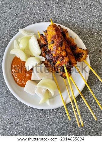 Chicken satay with Kuah Kacang or peanut sauce, cube cutting rice or Nasi Impit and sliced onion.