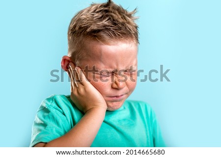 Child has earache. School boy has sore ear. Little kid covered ear with hand and closed eyes. Kid suffering from otitis. Vaccination for being health. Toothache. Royalty-Free Stock Photo #2014665680