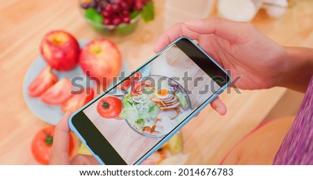 close up of Asian pretty woman holding smart phone - record her healthy meal with fruits and vegetables