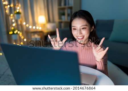 Sign language - Hearing impaired girl wearing winter cloth is making a love sign to her friend on video call online by laptop at home