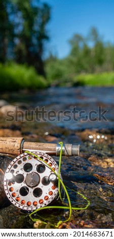 A fly fishing rod and reel on the river bank. Fishing scene on the banks.