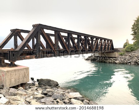 A closeup of a metal truss bridge over a river on a cloudy day Royalty-Free Stock Photo #2014688198