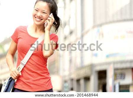 young asian woman on the phone walking at shopping street 