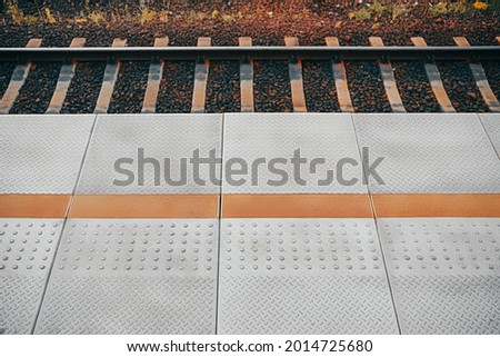 Train platform with tactile dotted pavement for handicapped people. City transportation infrastructure for people with visual impairment. Railway station floor. Rail and sleepers.
