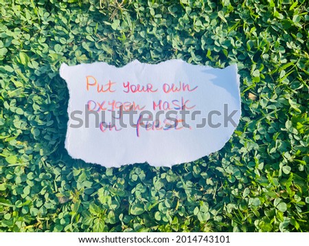 Put your own oxygen mask first. Handwritten message. Green grass as background.