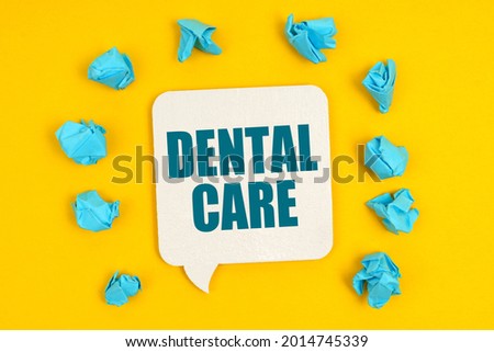 Medicine concept. On a yellow background, blue pieces of paper and a sign with the inscription - DENTAL CARE