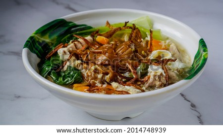 Flat Noodles cooked in Egg Gravy (Wan Tan Hor) with chicken bits and fish balls. Garnished with fried onions. A chinese cuisine served in Southeast Asia.