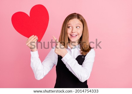 Photo of shocked cute school girl wear white black uniform smiling pointing looking big red heart isolated pink color background