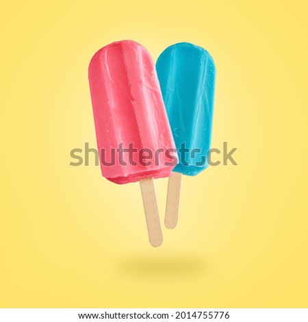 Red and blue ice creams flying on yellow background with copy space. Summer background
