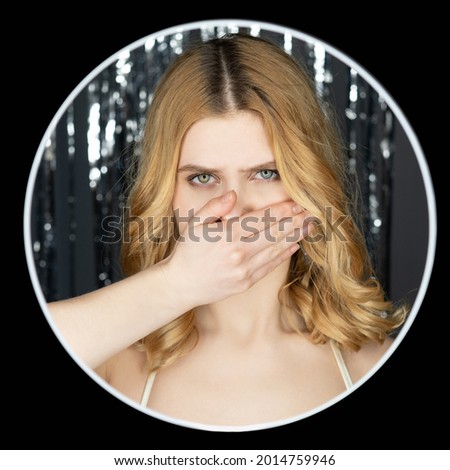 Silent woman. Holiday secret. Festive celebration. Speechless gloomy lady curly hair closing mouth with hand on silver shimmering cascade curtain background black circle frame.