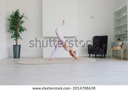 Health concept. Young beautiful woman does yoga exercise in a modern room