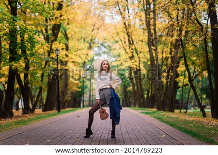 Beautiful woman playing ukulele guitar at outdoor in an autumn forest