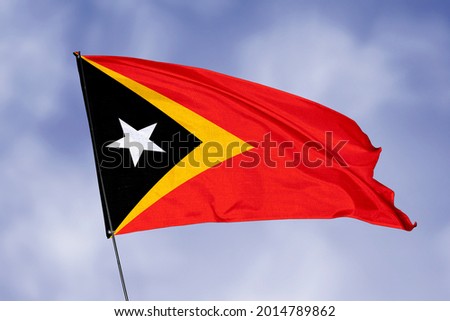 East Timor flag isolated on sky background. National symbol of East Timor. Close up waving flag with clipping path.