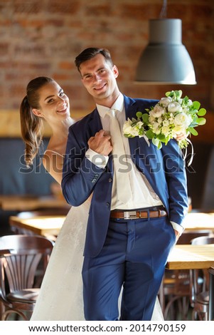 Elegant couple is having a photo taken in the restaurant after the ceremony. 
