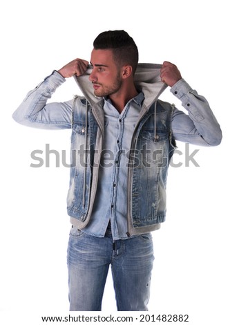 Handsome young man in hoodie, denim vest and jeans, isolated on white