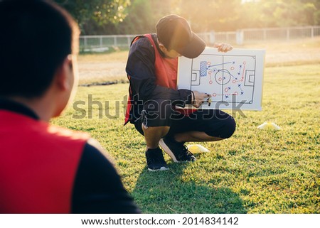 Coach training a tactic for asian teenager football player. Royalty-Free Stock Photo #2014834142