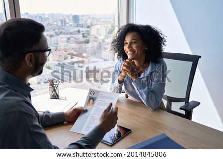 Friendly interview between Indian businessman hr director holding paper cv hiring for job female African American applicant manager sitting in contemporary office. Human resources recruitment concept. Royalty-Free Stock Photo #2014845806