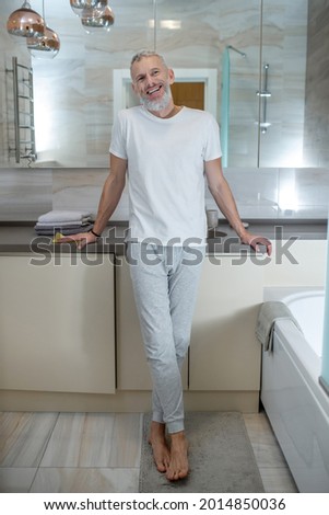 A tall mature amn standing in a bathroom and looking positive