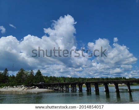 The magnificent Old bridge at Summerville beach running through it. The bridge's reflection is shown perfectly above the water while clouds hover above it.