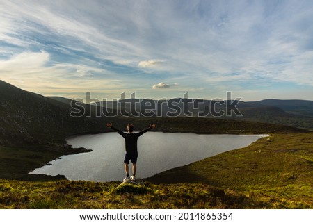 Man raising his arms admiring the lough ouler in the Wicklow Mountains Ireland