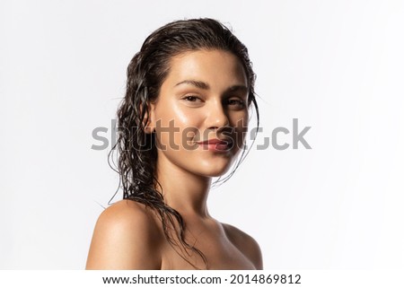 Beautiful young woman with clean perfect glowing skin, wet hairs. Portrait of smiling girl with bare shoulders on gray studio background. Skincare and wellness. Natural woman beauty. Royalty-Free Stock Photo #2014869812