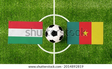 Top view soccer ball with Hungary vs. Cameroon flags match on green football field