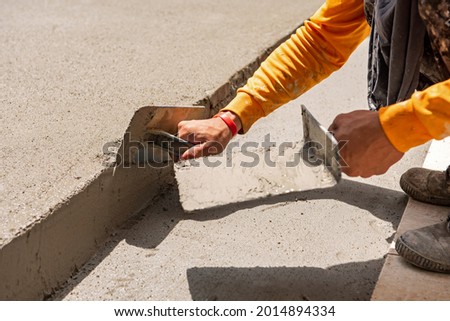 Man working concrete plastering the floor. Hand smoothing the mortar applied on the floor with a plastering trowel.