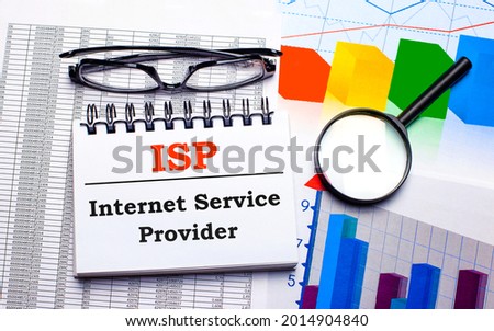 On the desktop are glasses, a magnifying glass, color charts and a white notebook with the text ISP Internet Service Provider. Business concept. View from above Royalty-Free Stock Photo #2014904840