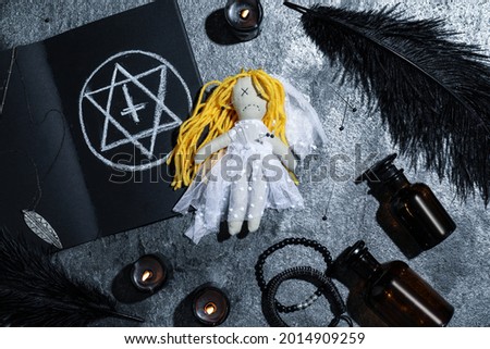 Bride voodoo doll with pins surrounded by ceremonial items on grey table, flat lay