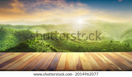 Brown blank wooden table top with the mountain landscape. table background of free space for your decoration and blurred landscape of mountains. orange sky sunset in the evening.