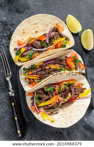 Mexican tacos shells with beef meat, onion, tomato and sweet pepper. Black background. Top view