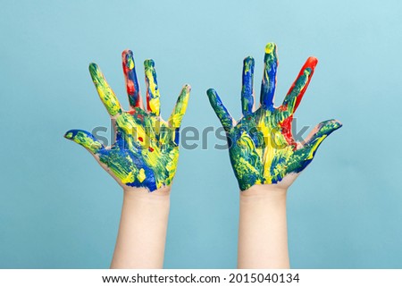 Photo of a woman's hand with her fingers spread apart with multicolored acrylic paints
