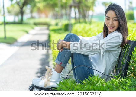 Asian woman wearing roller skates sitting in a garden chair 