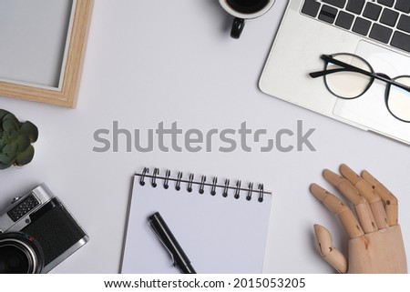 Mock up and above view with notebook computer, eyeglasses, camera, photo frame, note, pen and hand model on white background.