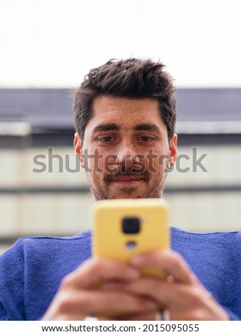 Detail of a Hispanic man with freckles looking at the mobile phone. Social networks, new technologies. Vertical photo
