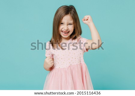 Little fun cute kid girl 5-6 years old wears pink dress doing winner gesture say yes isolated on pastel blue color background child studio portrait. Mother's Day love family people lifestyle concept Royalty-Free Stock Photo #2015116436