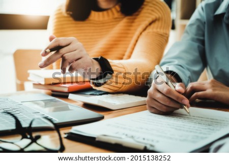 focus consultant holding a pen and the business owner holding a pen reading the terms of a joint venture contract with a partner company.
