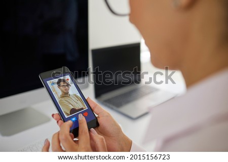 Search for love. Close up of young woman flipping through profiles of men in dating app on mobile phone. Woman is about to press a red heart button in sympathy with the man who appeared on the screen.