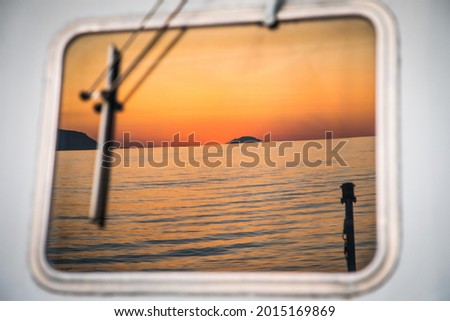 sunsets over the ocean, reflected in the windows of a ship