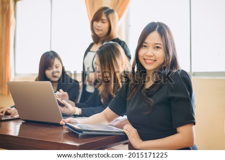 Portrait of a beautiful authentic satisfied business woman looking at camera with team at behind. Concept for leadership and successful startup millennial.