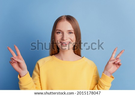 Portrait of charming pretty friendly lady show v-sign white smile on blue background