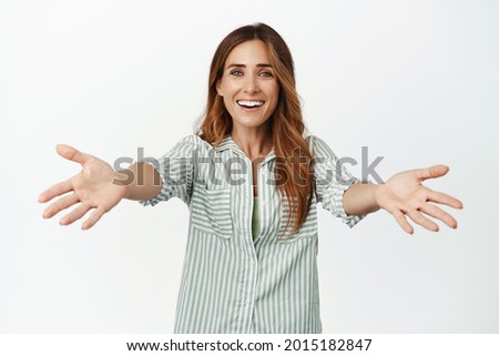 Image of smiling adult woman reaching hands forward for hug, warm welcome, hugging or cuddling, stretching arms at camera, standing over white background Royalty-Free Stock Photo #2015182847