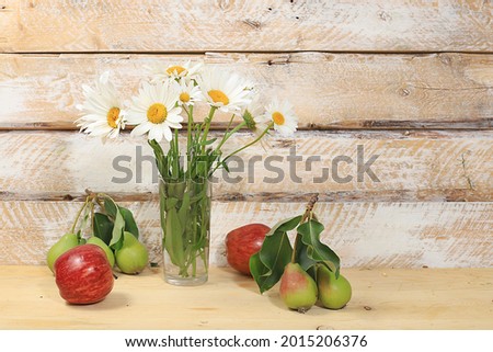 Bouquet with chamomiles and ripe apples and pears on a wooden table, rustic style.Abstract floral arrangement, autumn background, minimal holiday concept. Mother's day card, happy birthday, wedding,