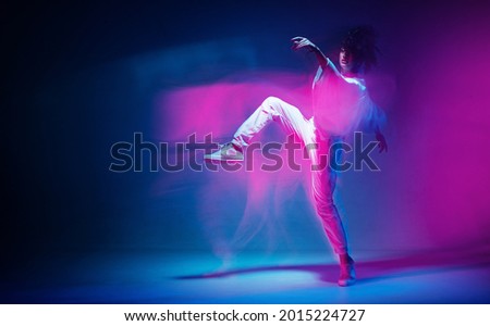 Dancing sportive female in colorful neon light. Expressive contemporary dance. Studio photography with long exposure