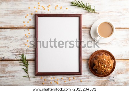 Brown wooden frame mockup with cup of coffee and cake on white wooden background. Blank, top view, flat lay, still life.