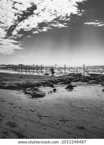 silhouette of a man entering the sea on the beach in black and white