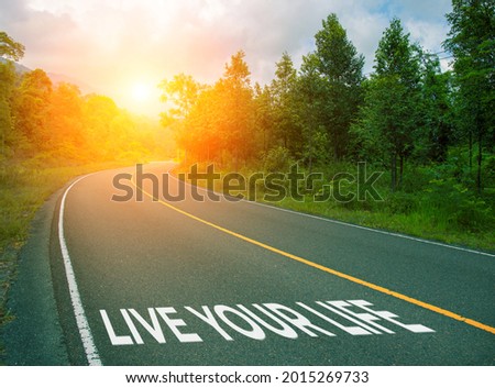 Live your life, concept photo of asphalt road. Encouraging quote on road. Summer forest landscape with curved highway. Inspirational quote banner. Motivational card. Life mastermind concept