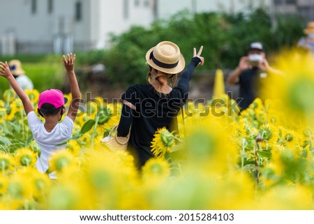 Father taking pictures of boy and mother in sunflower field